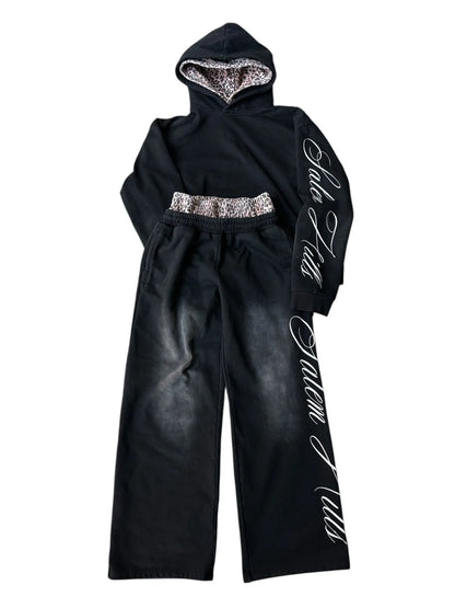 Man wearing a black punk print hoodie and matching trousers, a casual lounge suit set.