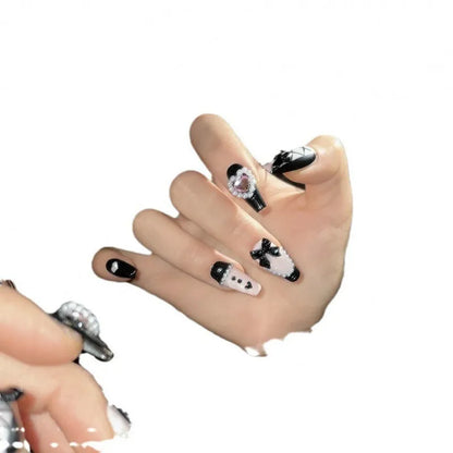 Hand-painted black and pink heart design on reusable plastic false nails with bow and cat's eye details.