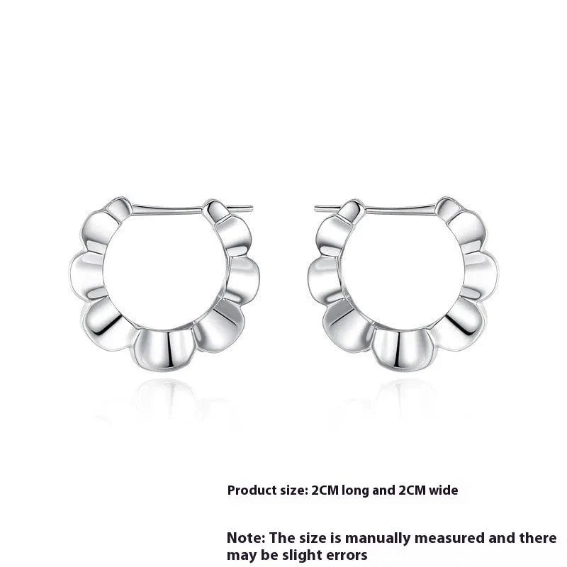 A pair of sterling silver geometric stud earrings with a round centre and butterfly clasp on a grey background.