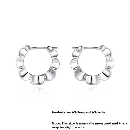 A pair of sterling silver geometric stud earrings with a round centre and butterfly clasp on a grey background.