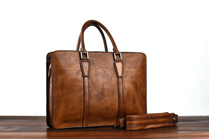 Men's khaki retro leather handbag with horizontal square shape and zipper top, shown on a desk.