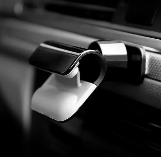 Black universal car phone holder with 360-degree rotating pivot mounted on a car air vent, holding a mobile phone.
