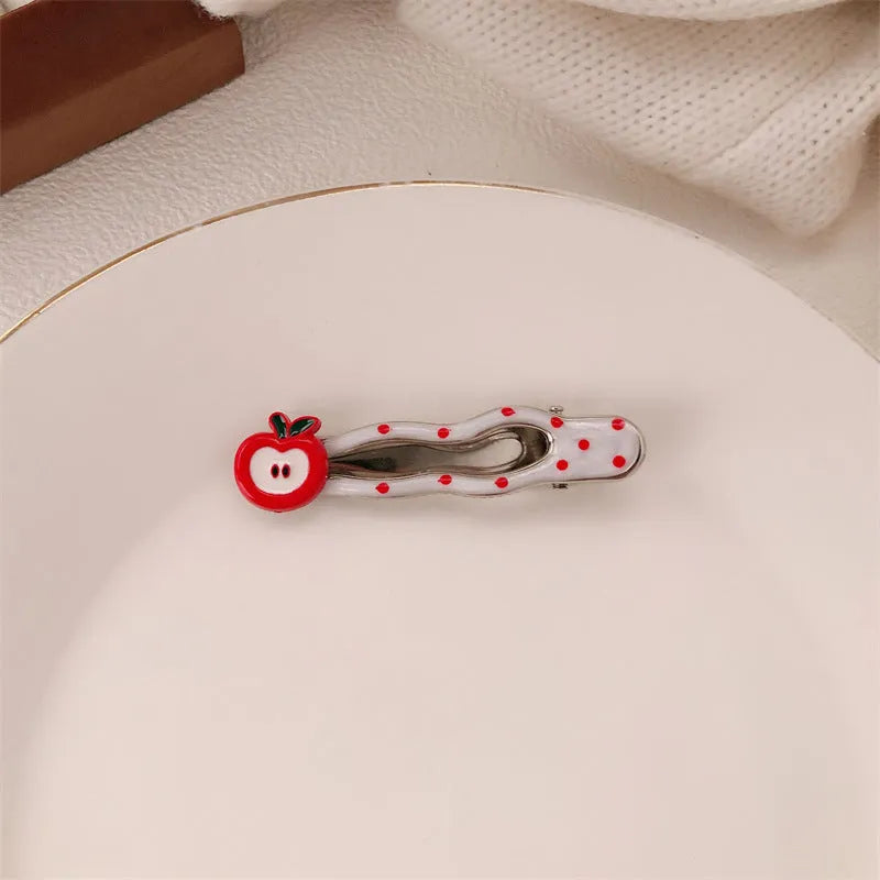 Red plastic hair clip with a 3D love heart and dots on a willow leaf-shaped base.
