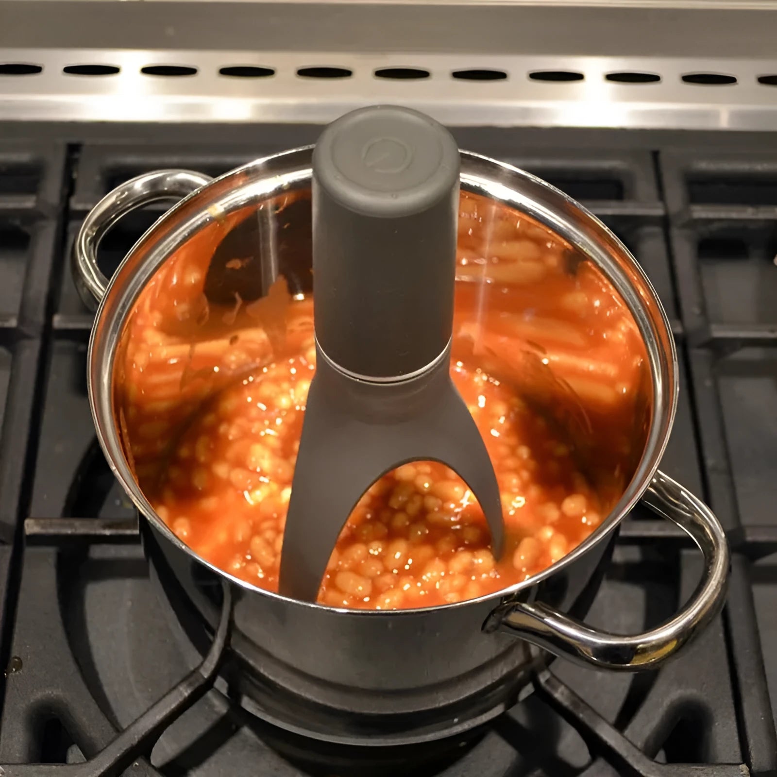 Uutensil Stirr automatic electric kitchen mixer device in green, shown next to a saucepan.