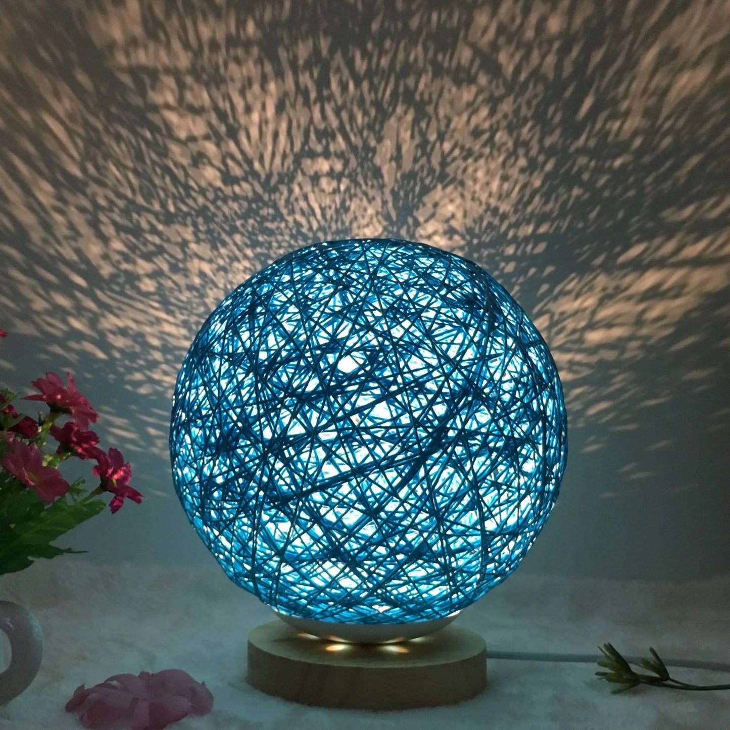 Spherical hand-knitted rattan table lamp with remote control on a wooden desk
