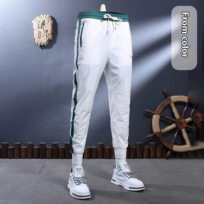 Men's ice silk skinny sports pants in black or white with striped tapered leg and ankle-tied hem