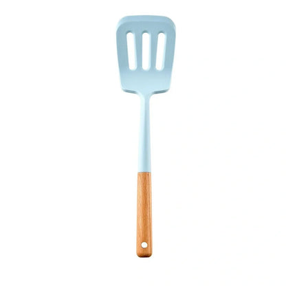 Blue silicone non-stick cookware set with frying spatula, colander, egg beater, and white iron storage bucket for kitchen organisation