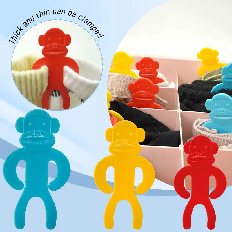 Set of blue, red, and yellow plastic socks clips on a pair of grey socks.