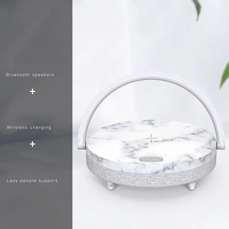 Wireless charging LED night light with Bluetooth speaker in marble pattern finish on a wooden desk.