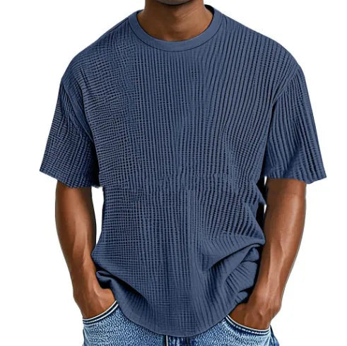 Man wearing a light blue waffle-textured cotton blend short sleeve t-shirt, casual pullover style.