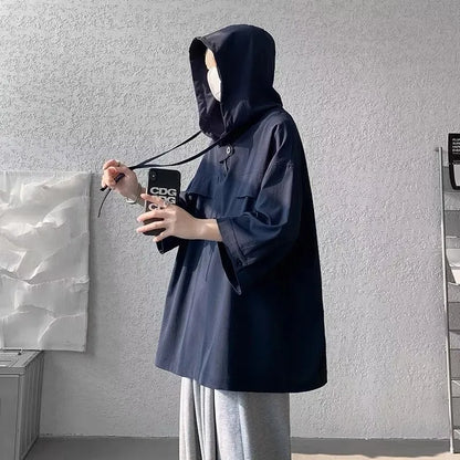 A man wearing a loose-fit black hooded short sleeve t-shirt for summer.