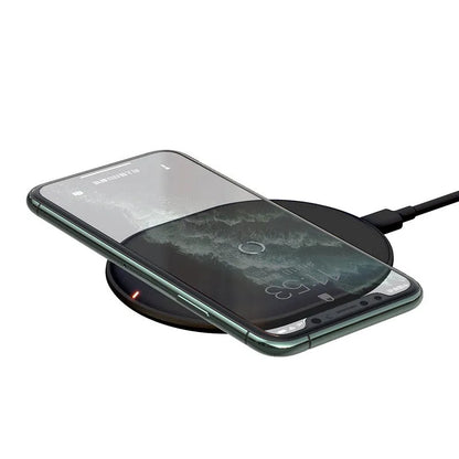 Black Baseus 15W wireless charging pad with textured silicone surface on a wooden desk.
