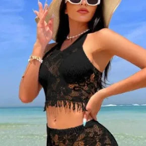 Women's white two-piece swimsuit with lace bikini top and tassel skirt on beach
