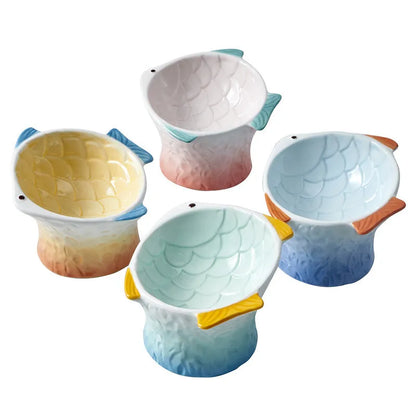 Set of four blue fish-shaped ceramic cat bowls with tilted design on a wooden table