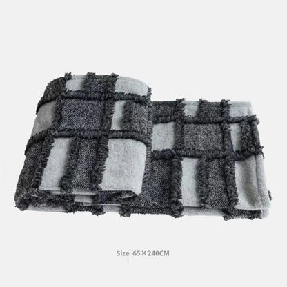Grey and white plaid bed runner blanket with coordinating pillowcase and round leather pillow on bed