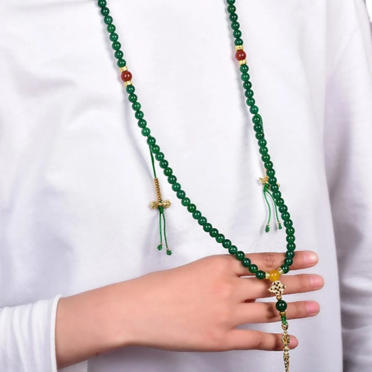 Close-up of a multi-strand green agate bracelet with natural stones on a wrist.