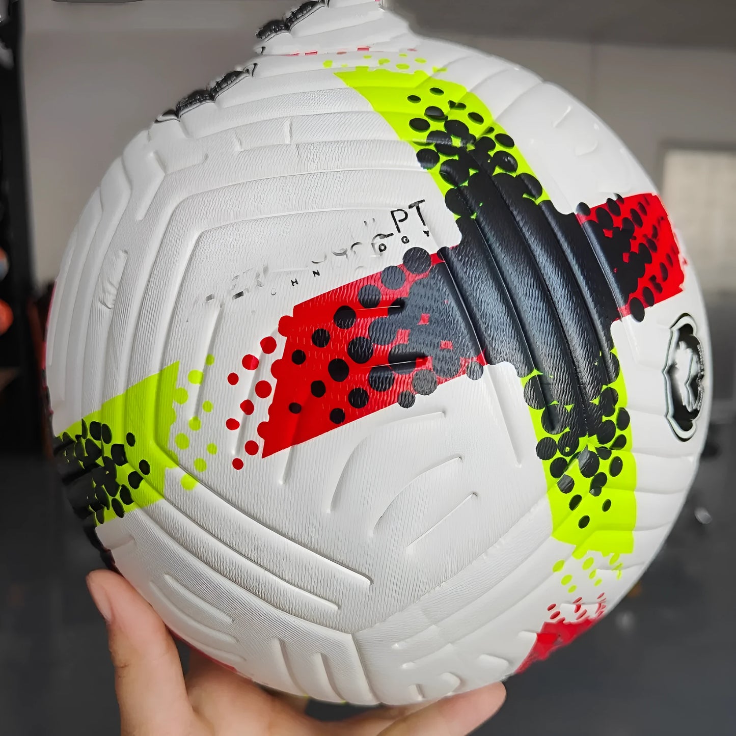 Fluorescent green Size 5 football with seamless patch construction on a green pitch.