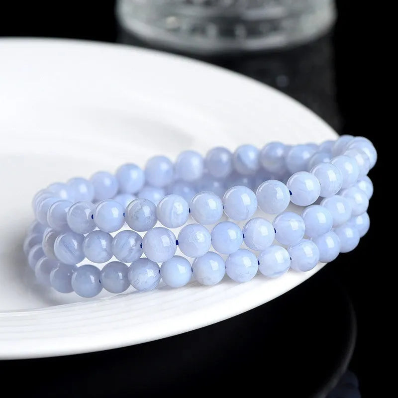 Blue agate bracelet with 6-6.8mm beads in multi-circle pattern and Ruyi elements on a wrist.