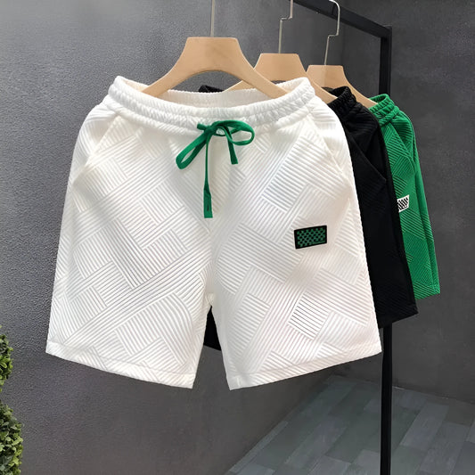 Man's solid colour casual sports shorts in micro-elastic polyester fabric on a beach background