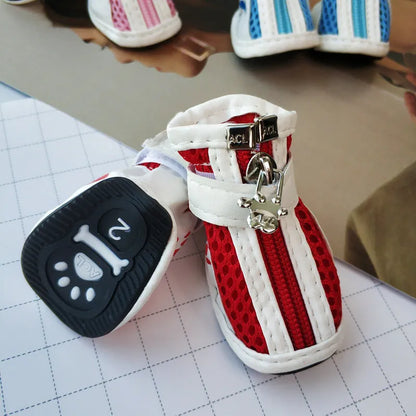 Four blue cloth dog shoes with zippers and non-slip soles laid out for a small dog.