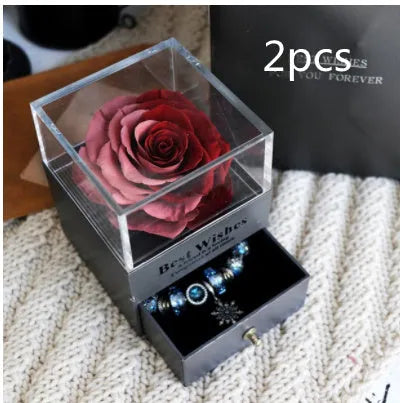 Blue and pink eternal flower gift box with roses and carnations on a table.