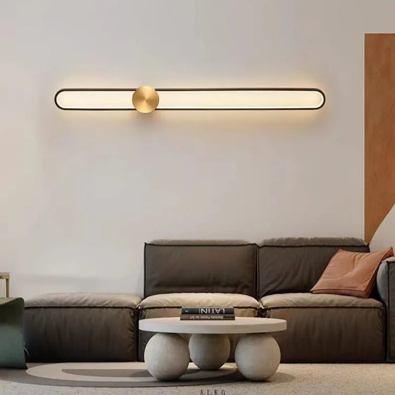 Round black iron wall sconce with integrated LED light glowing on a modern grey wall