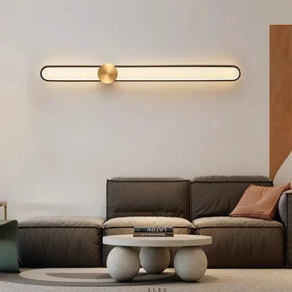 Round black iron wall sconce with integrated LED light glowing on a modern grey wall