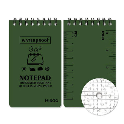 Spiral-bound waterproof notepad in camouflage colour, open on a desk with a pen, showing stone paper pages.
