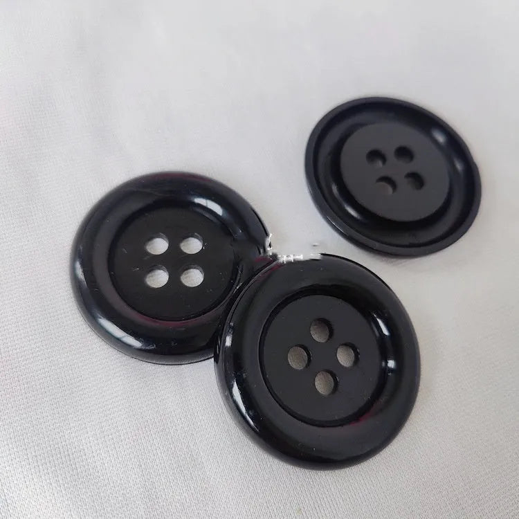 Assorted oversized round plastic buttons in various colours showing four-hole sew-through design.