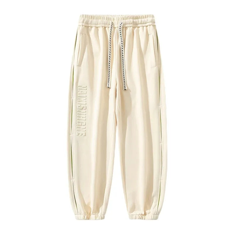 Men's ankle banded trousers in micro-elastic cotton with collage stitching details, showing loose fit and tapered leg