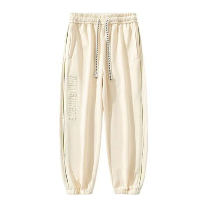 Men's ankle banded trousers in micro-elastic cotton with collage stitching details, showing loose fit and tapered leg