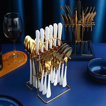 24-piece stainless steel cutlery set with knives, forks, spoons, and teaspoons on a storage rack in a gold finish.
