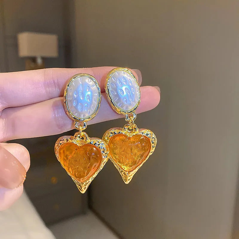 A pair of silver-tone stud earrings with a textured pleated oval love heart shape in various colour options.