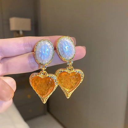 A pair of silver-tone stud earrings with a textured pleated oval love heart shape in various colour options.