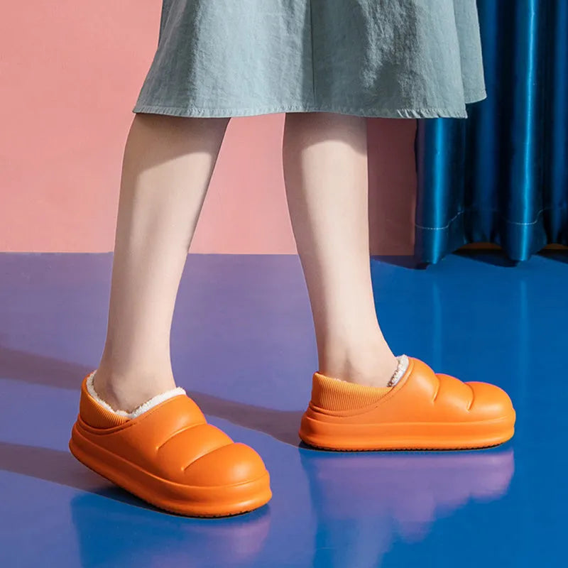 Yellow women's winter slippers with waterproof EVA sole and plush lining on a wooden floor.