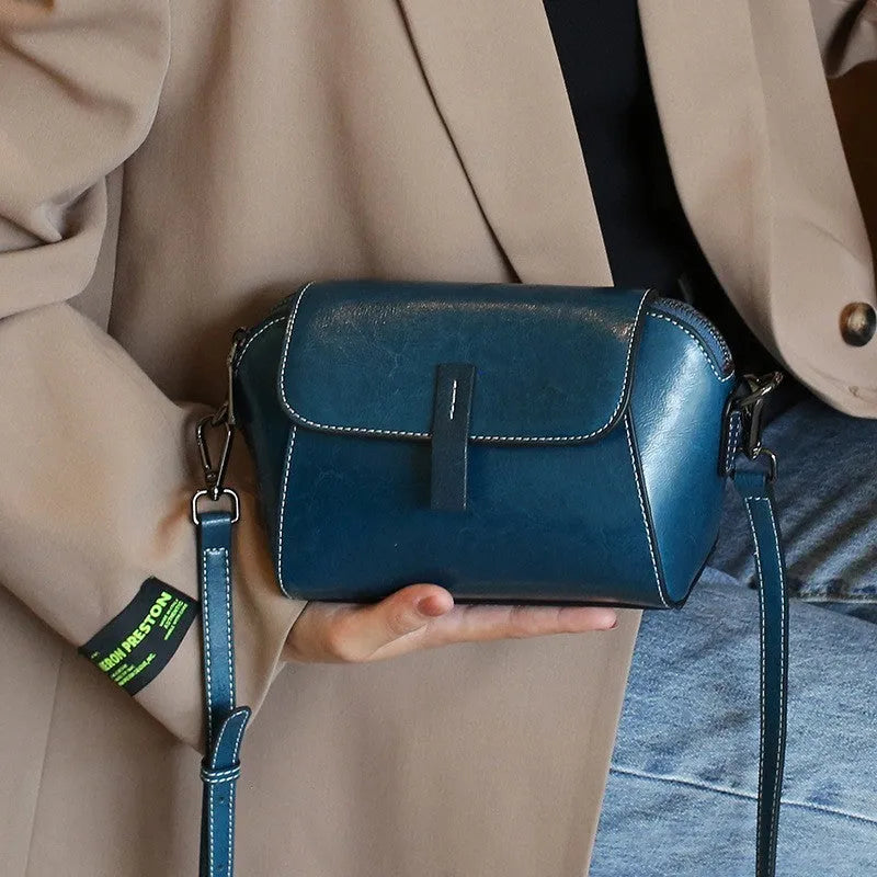 Women's brown shell-shaped genuine leather messenger bag with a single shoulder strap and visible stitching.
