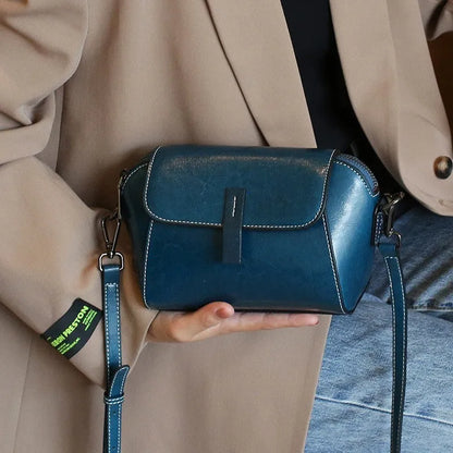 Women's brown shell-shaped genuine leather messenger bag with a single shoulder strap and visible stitching.