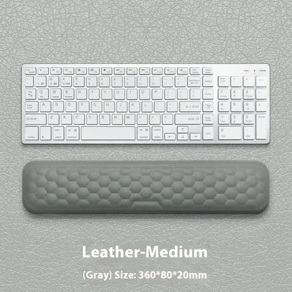 Black and grey memory foam mouse wrist rests with cloth and leather-style covers on a desk.