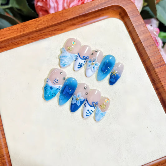 Set of 24 blue hand-painted false nails with carved floral design on transparent base, showing XS, S, M, L sizes.
