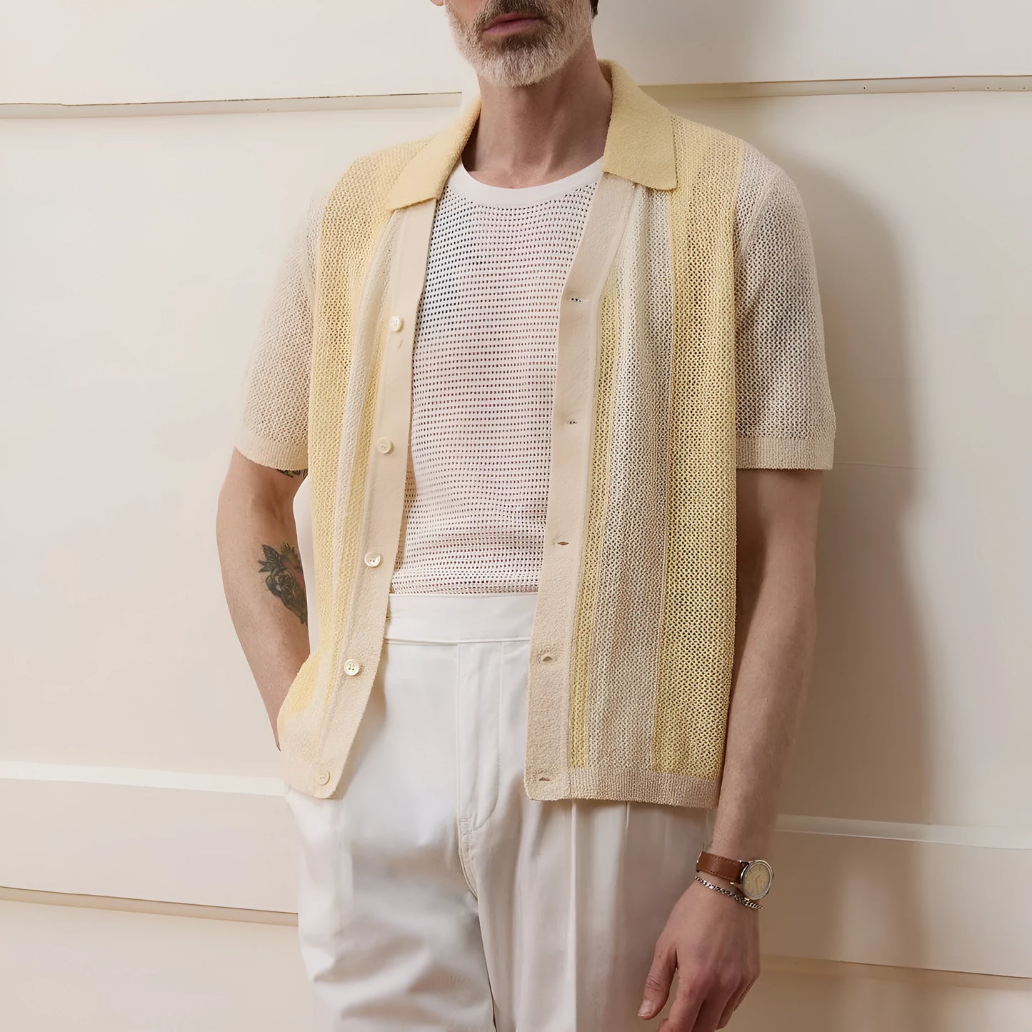 Yellow asymmetric short-sleeved polo shirt with hollow-out design on a hanger.