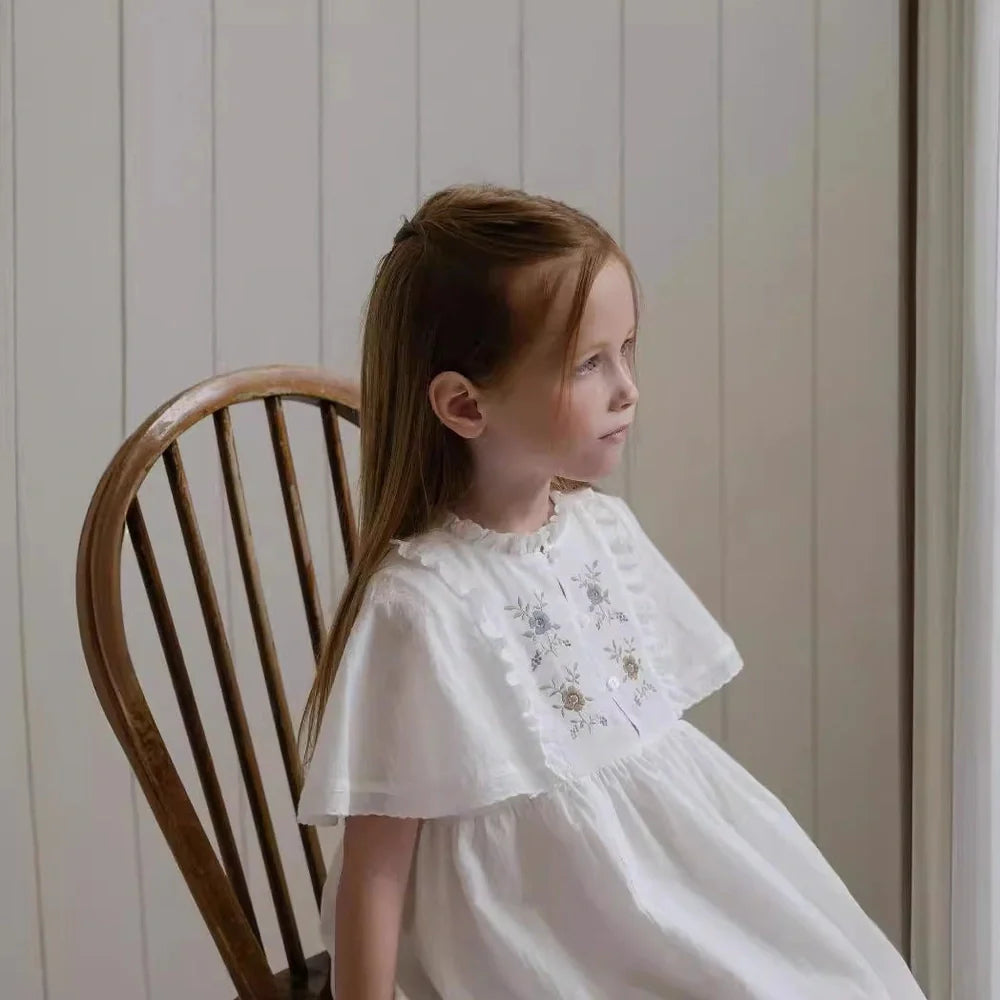 White cotton girls dress with embroidered skirt detail, short sleeves, and Western style silhouette