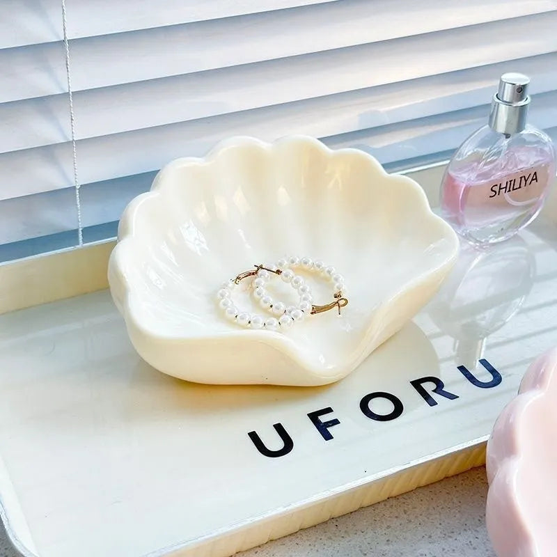 Plastic shell soap dish in pearl white, dimensions 12x9x5.5cm, on a bathroom counter