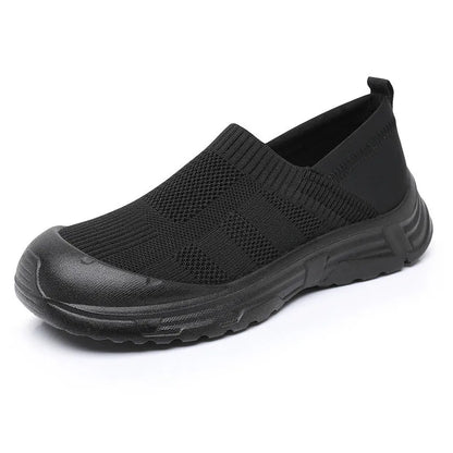 Women's one pedal slip-on shoe in black with cloth upper and PVC sole, showing round toe and flat heel design.