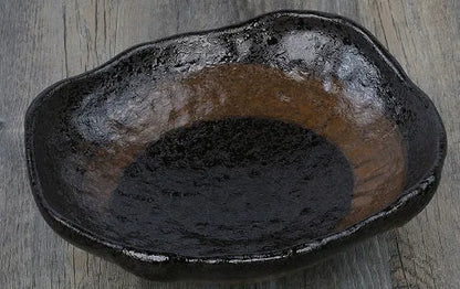 Japanese style irregular shaped ceramic sashimi bowl with floral decoration on table.