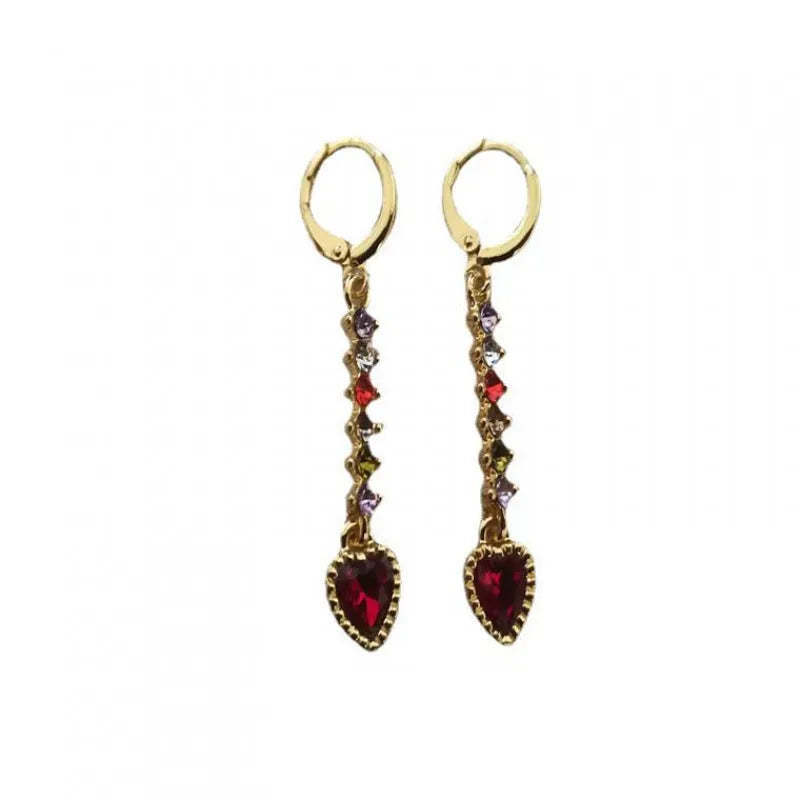 Women's gold and silver heart-shaped alloy drop earrings on a plain background.