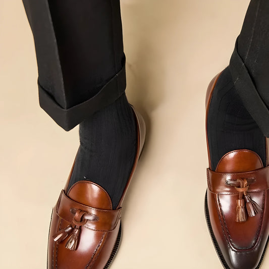 Men's black genuine leather tassel loafers with a rubber sole, shown from a side angle.
