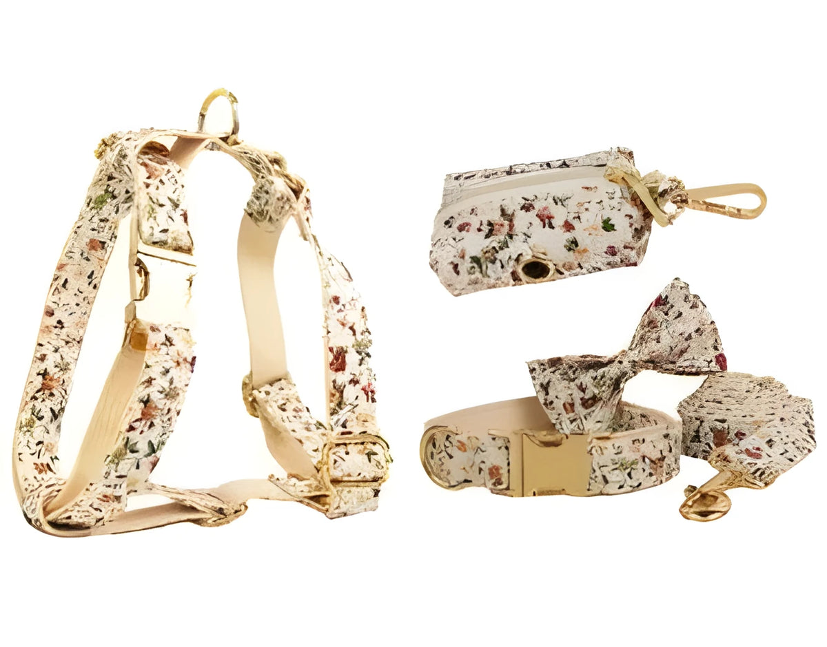 Small white flower patterned dog collar, leash, vest, bow, and poop bag holder set laid out flat.