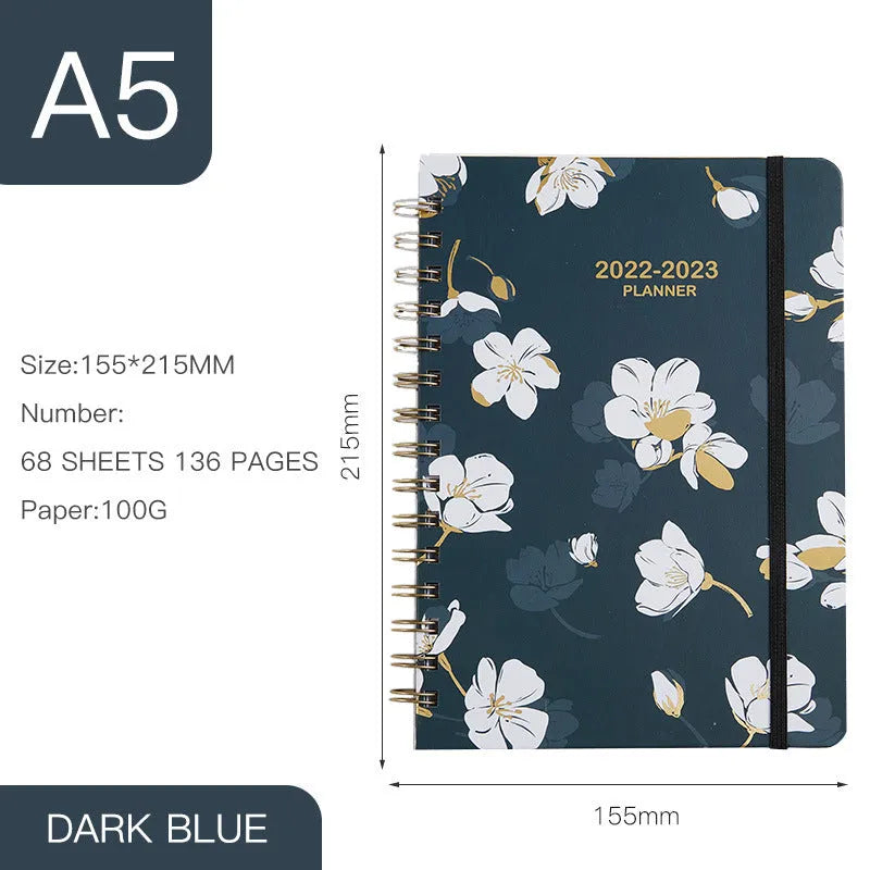 A5 spiral coil notebook open showing annual calendar pages and spiral binding
