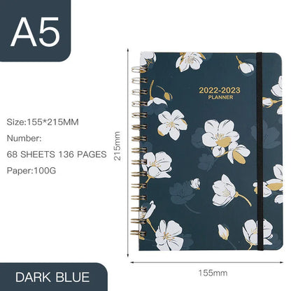 A5 spiral coil notebook open showing annual calendar pages and spiral binding