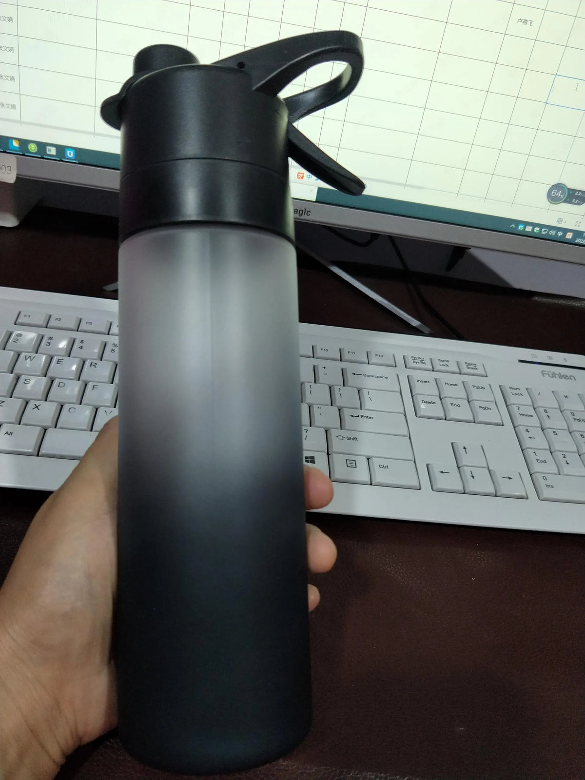 Large plastic spray water bottle with handle strap and leakproof lid in green colour.